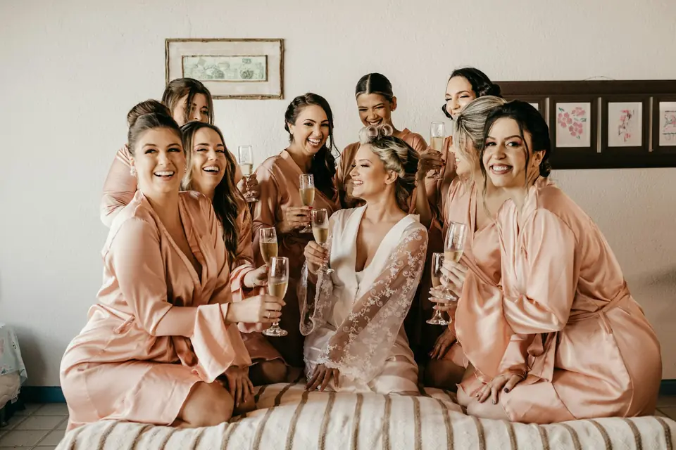 Bridesmaids in matching robes toasting with the bride