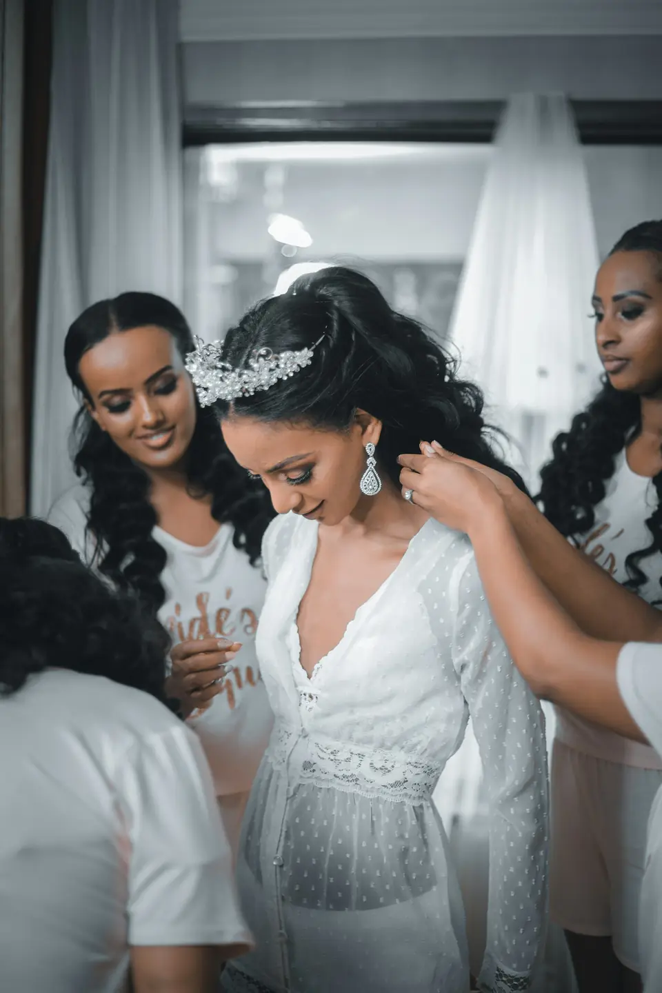 Bridesmaids helping a bride with her earrings and tiara