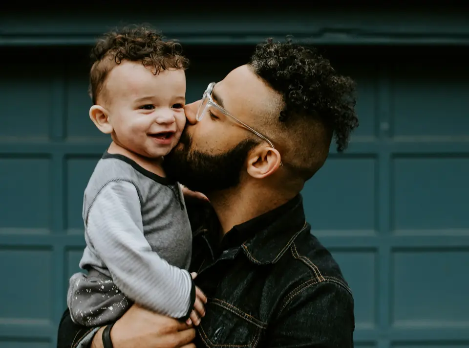 A father kissing his laughing toddler
