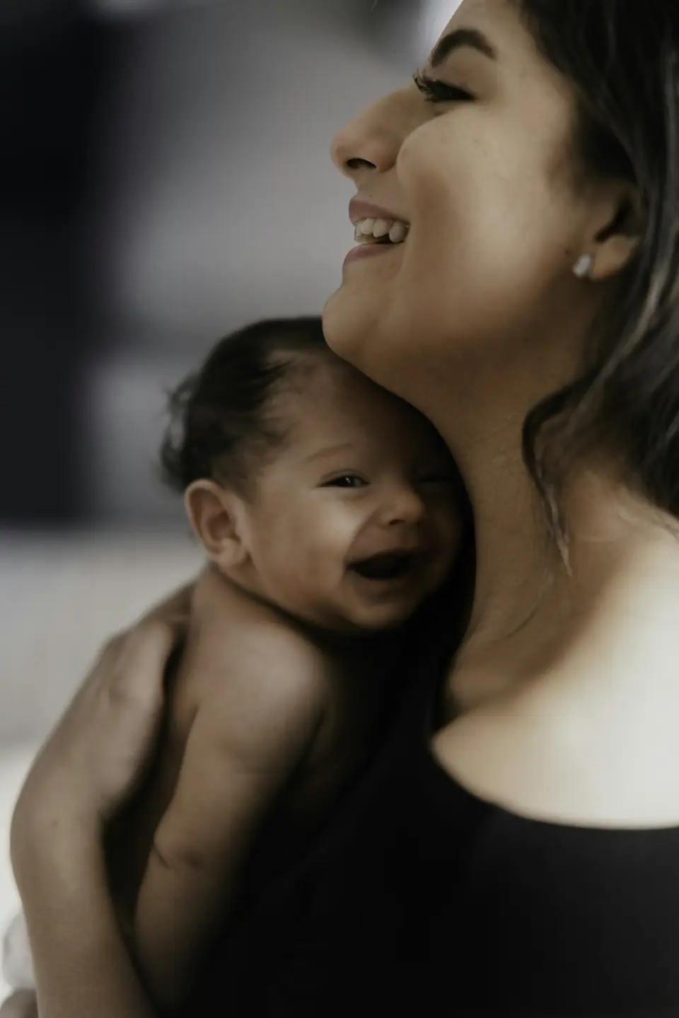 A smiling mother holding her laughing baby against her neck