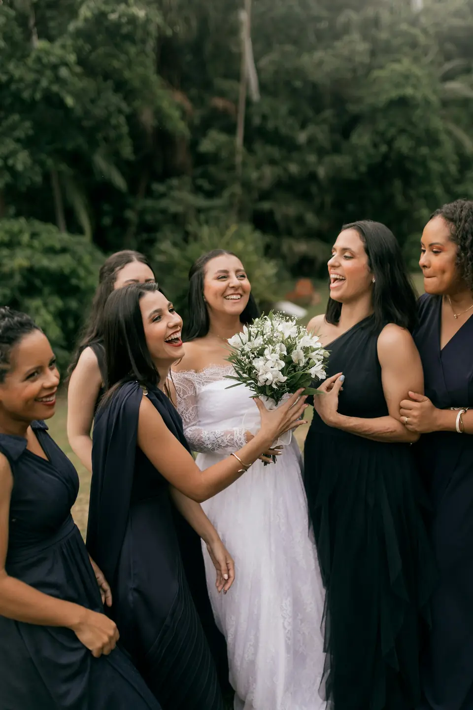 A bride laughing with her bridesmaids outdoors