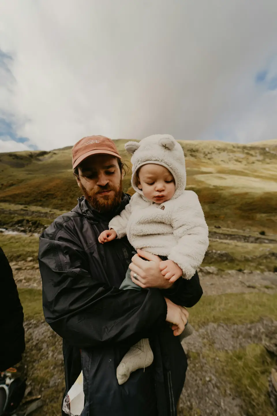 A father holding his baby on a grassy hillside
