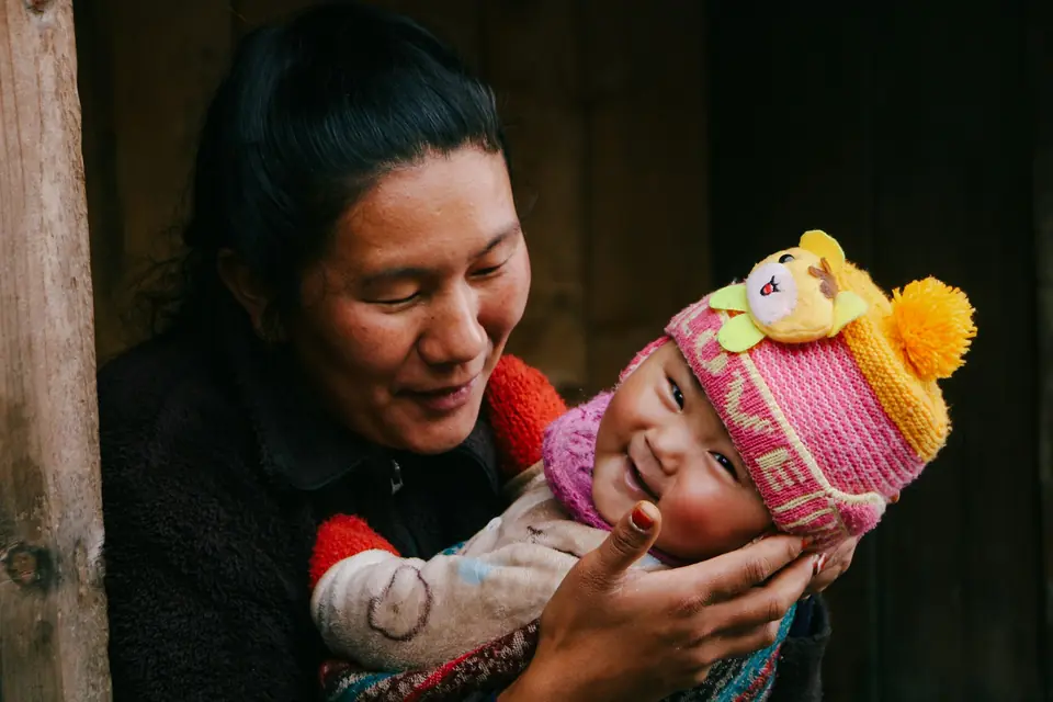 A mother smiling at the laughing baby she holds