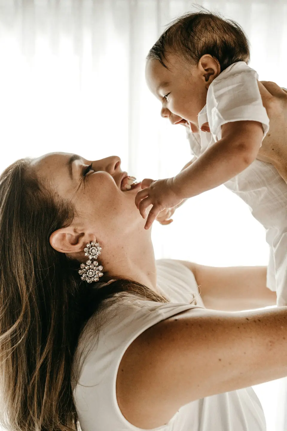 A woman lifting a baby up and laughing