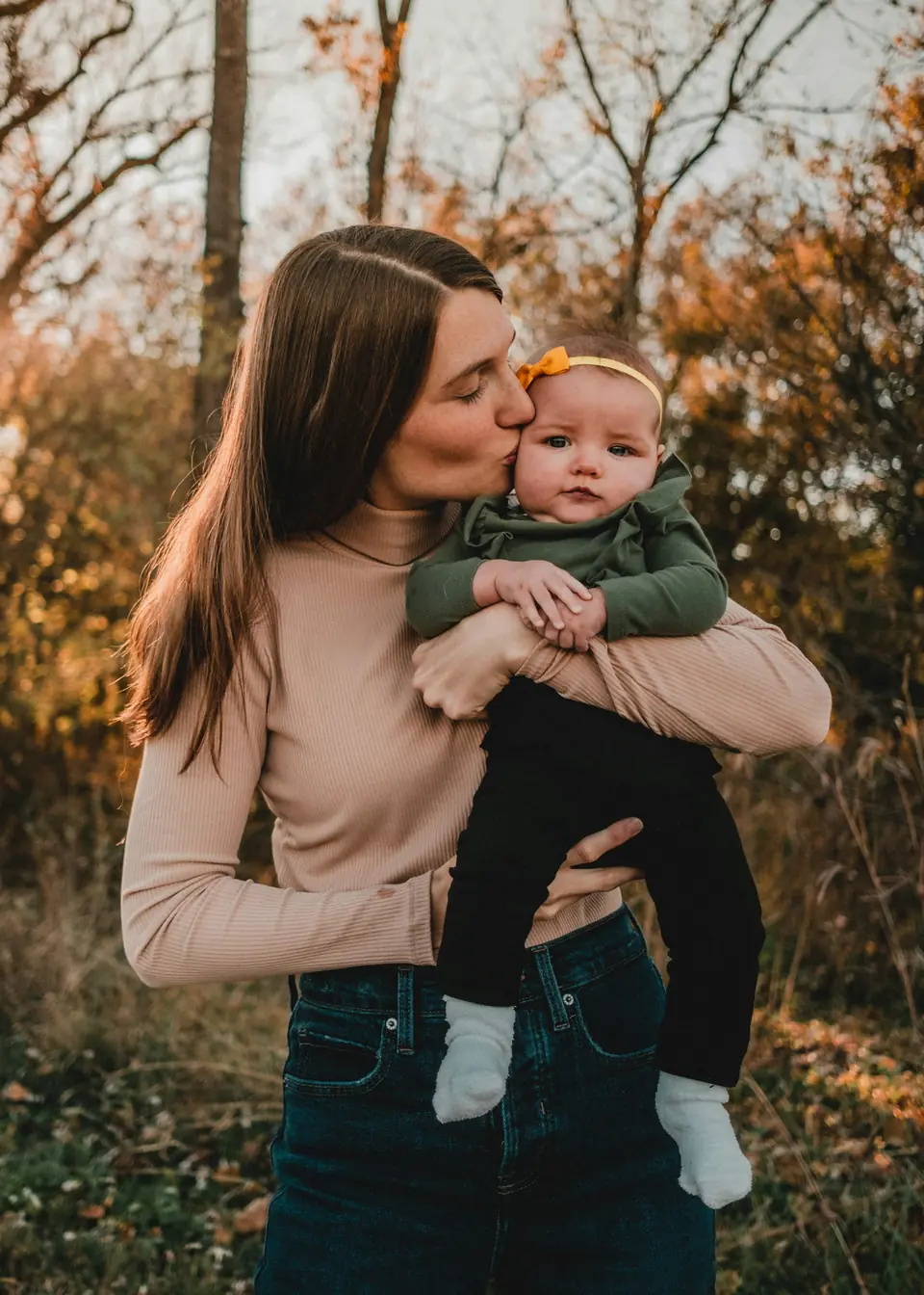 A woman holding a baby outdoors in autumn