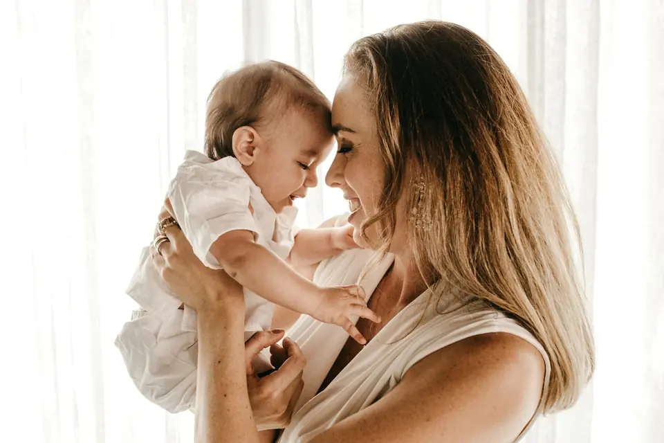 A smiling woman carrying her baby