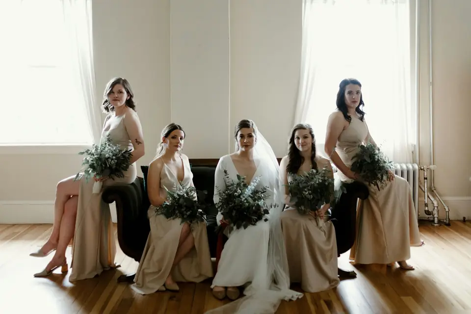 A bride and her bridesmaids seated together holding bouquets