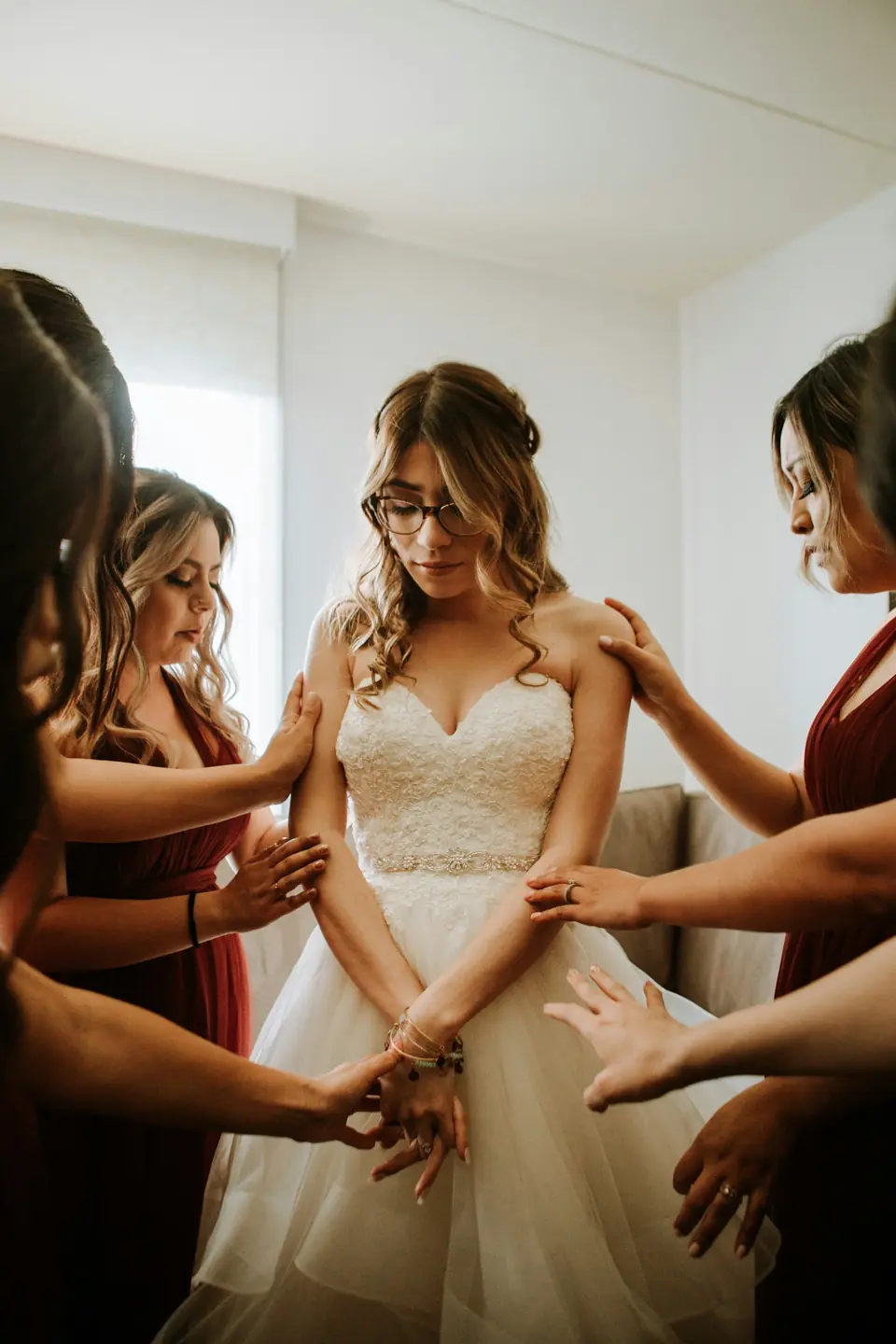 Bridesmaids helping a bride into her gown while she gets ready