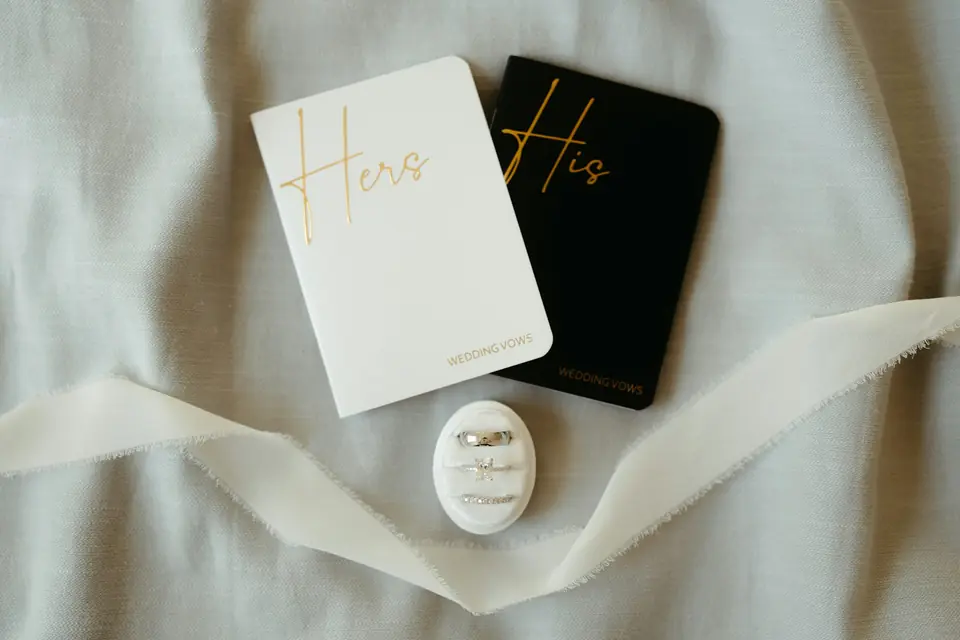 His and hers notebooks beside wedding rings