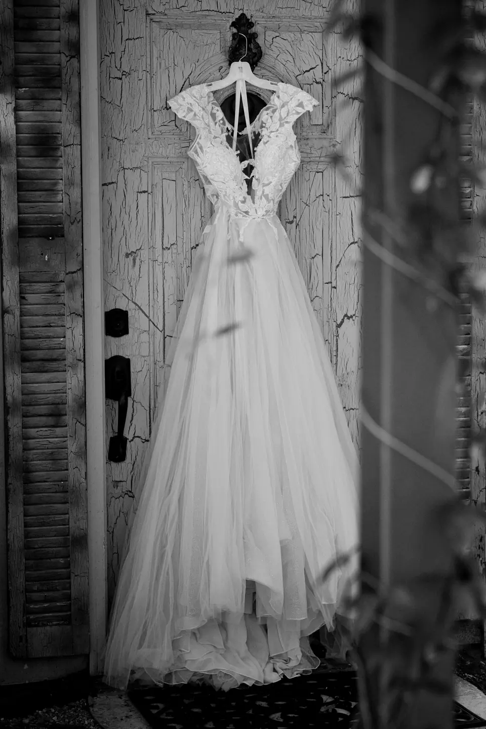 White wedding dress hanging on a brown wooden door